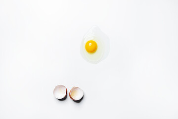 Raw egg with transparent white, yellow yolk and broken shell on white background