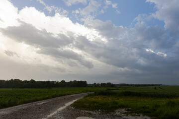 Fototapeta na wymiar Rain and storm clouds darken the sky over a country lane near Bergheim