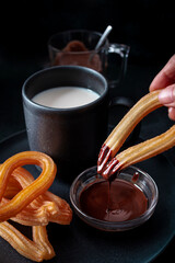 Hot chocolate with churros with dark background. Typical Spanish sweet breakfast. Food photography
