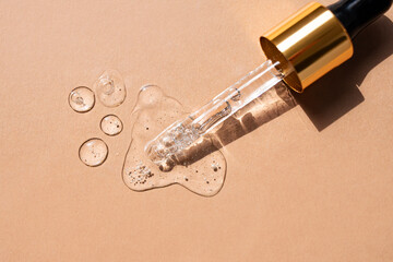 Serum drops and a pipette on a beige background. Top view.
