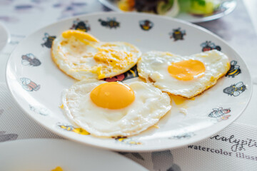 three fried eggs heart shape on white plate prepare for breakfast
