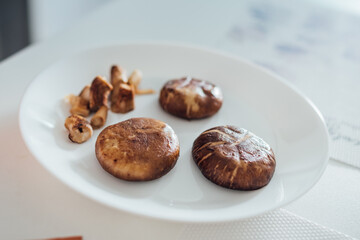 grill brown mushroom on white plate for prepare the breakfast.
