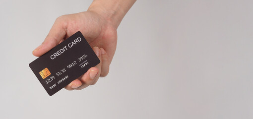 Hand is holding black credit card isolated on white background.