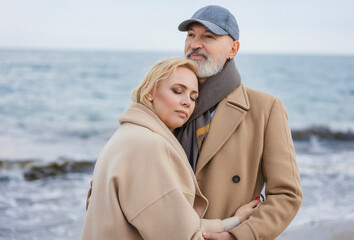 Aged couple walking along the beach against the background of the sea