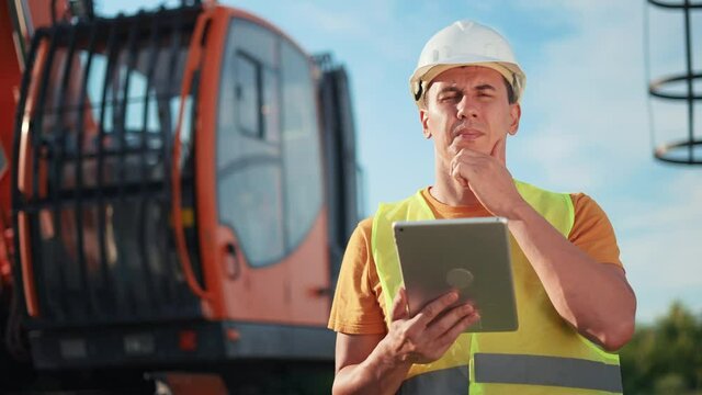 worker in hard a hat with digital tablet near excavator. construction site driver with online digital tablet. industry construction concept. worker hard hat near business excavator truck in uniform.