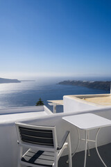 Obraz na płótnie Canvas Chair and table on terrace of luxury hotel. View of caldera. Santorini island, Greece. Volcano. Aegean sea. White architecture.
