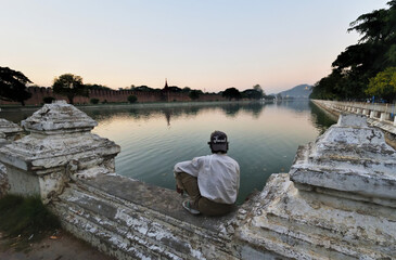 Crepuscular meditation contemplating the moats of the royal palace in Mandalay, Myanmar
