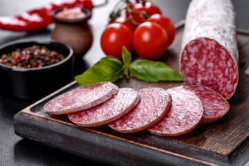 Spanish dried sausage salami on a dark concrete background
