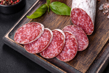 Spanish dried sausage salami on a dark concrete background