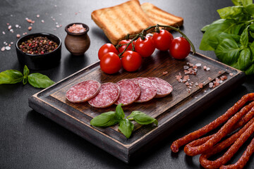 Spanish dried sausage salami on a dark concrete background