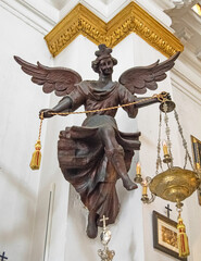 Figure of a bronze angel hanging on the side of the altar of a church © Maria