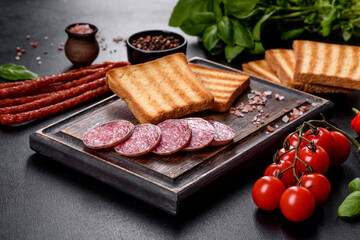 Spanish dried sausage salami on a dark concrete background