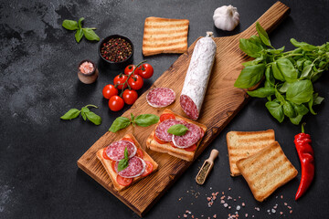 Spanish dried sausage salami on a dark concrete background