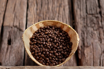 Coffee Beans Peaberry small size picking in bamboo basket. log wooden background. Selective focus on foreground with copy space.