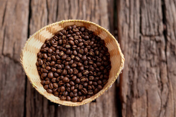 Coffee Beans Peaberry small size picking in bamboo basket. log wooden background. Selective focus on foreground with copy space.