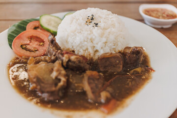 Thai stewed beef with rice served on white dish in the cafe.