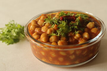 Chickpea in a thick gravy of onions tomatoes and spices. Served in a glass bowl.