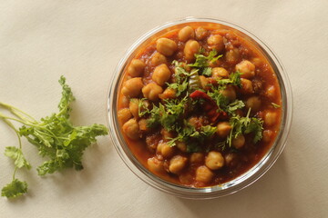 Chickpea in a thick gravy of onions tomatoes and spices. Served in a glass bowl.