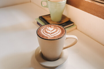Hot latte coffee served in white mug on the table in warm morning.