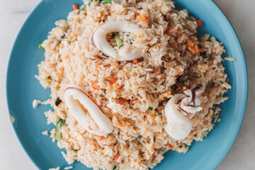 Thai style Squid Fried Rice served in blue ceramic dish on white table.