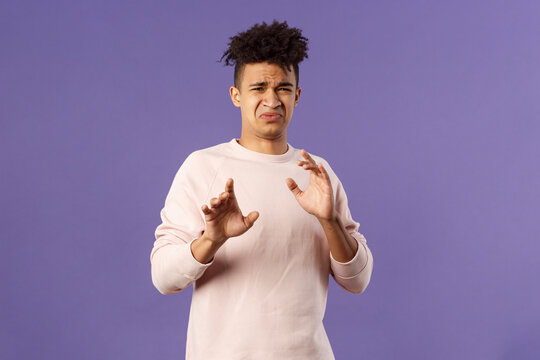 Phew Get It Away From Me. Portrait Of Disgusted Young Man Smelling Something Awful, Step Away And Blocking It With Raised Arms, Refuse Grimacing With Aversion And Reluctance, Purple Background