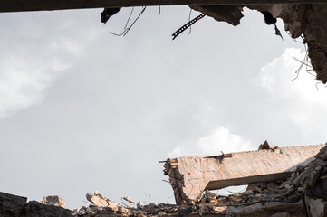 The ruins of the remains of a building with a concrete beam against the gray sky. Background.