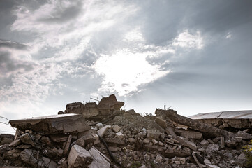 A pile of construction debris made of concrete fragments of slabs, beams and bricks against the...