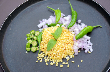 closeup the fried yellow gram split lentils with mint ,green chilly, sliced onion, over out of focus black brown background.