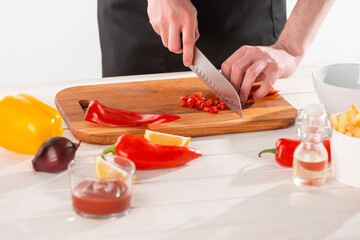 Man cutting red pepper on a wooden board