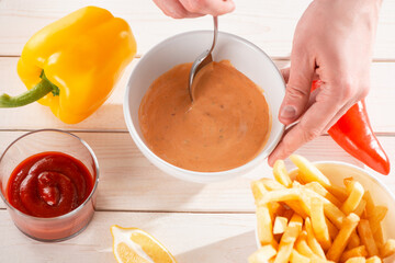 Top view on a hand mixing sauce andalouse with a spoon
