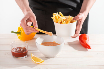 Man dipping French fries into homemade sauce andalouse