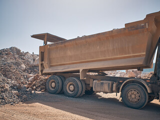 Unloading tipper. Earthmoving works at construction site. Dump truck unloads soil from truck back
