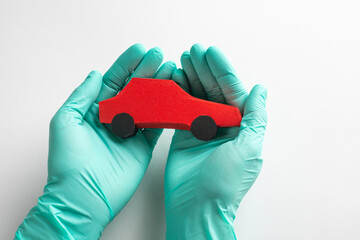 Hand in gloves holding a red paper car toy on white background
