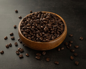 Coffee beans in wooden bowl on grunge background.