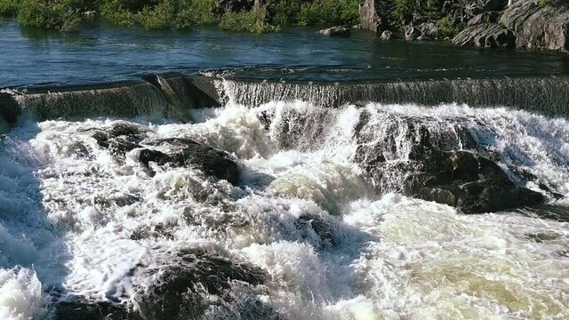 Hydroelectric dam with flowing water. Fairy waterfall at wild forest. Wonderful fresh water waterfalls river flowing. Forest rocks with a roaring stream running. 4K and slowmotion.