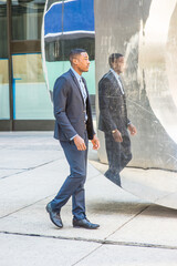 A young black businessman is walking, passed by a mirror wall,  and thinking..