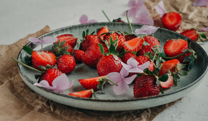 Ripe farm strawberries in a plate flowers on a white background, fresh juicy strawberries in a ceramic green plate
