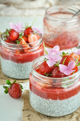 Healthy strawberry fruit dessert with milk and chia seeds in jar on light background. Healthy raw vegetarian dessert.