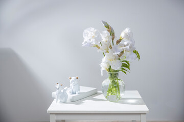 A vase with white iris, pieces of paper, a figurine with a fox. Scandinavian style.