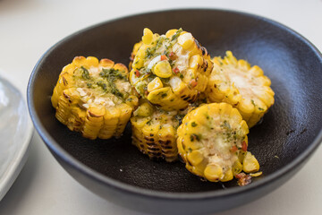 Chopped, grilled spiced corn in a black ceramic plate
