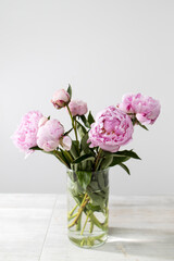 Bridal bouquet of pink peonies in a glass vase on a wooden table