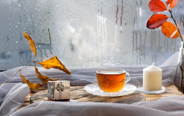 A cup of tea on the window with raindrops in autumn. The season when you need warm drinks and care.