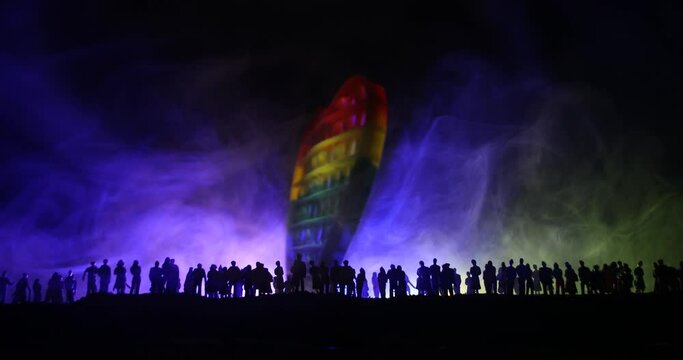 lgbt rights concept, Silhouette of crowd standing against a heart painted like a LGBT flag in dark background. Selective focus