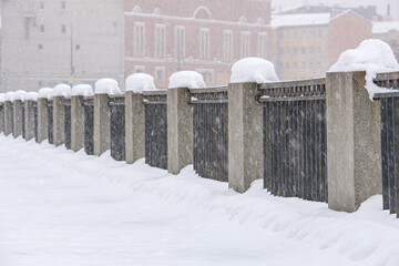 severe blizzard on the city embankment with granite fences