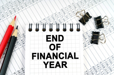 On the table are reports, pencils and a notebook with the inscription - END OF FINANCIAL YEAR