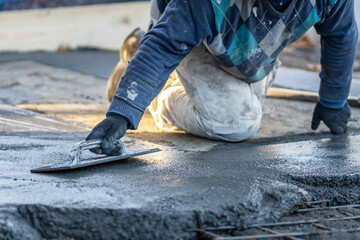 Close up on midsection of unknown worker spreading concrete cement mortar on the ground in day at...