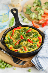 Omelet with vegetables: broccoli, pepper and green peas. Frittata in a frying pan. Selective focus