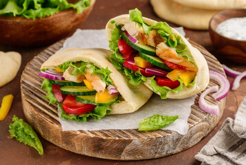 Pita with roasted chicken and vegetables: cucumber, tomato, pepper, red onion and yoghurt sauce. Healthy food. Selective focus 