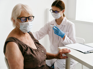 Nurse giving an elderly woman a covid-19 injection passport treatment