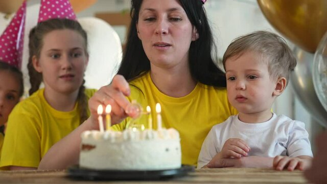 birthday. happy family on holiday party. parents and fun childs with baby getting ready to blow out birthday cake with candles. happy family at birthday. baby blows out the candles on the cake